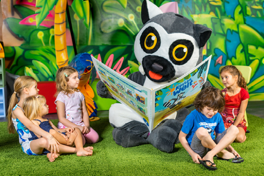 Fünf Kinder sitzen um Katta herum, der ihnen vorliest