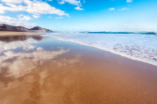 Einsame Strand von Cofete auf Fuerteventura, links die kahlen Felsen, rechts das Meer